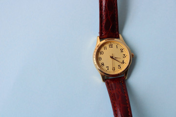 Gold and quartz watch on a blue background.