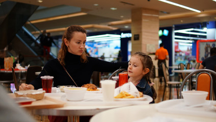 Cute little girl with young mother in restaurant