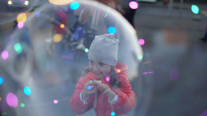 Happy girl smiling behind big soap bubble.