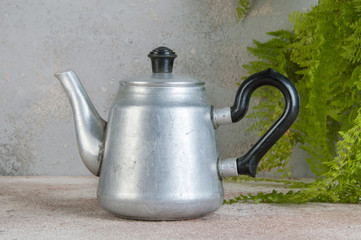 Silver metal tea pot on concrete background.