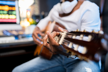 Hands of young musician of African ethnicity on strings of acoustic guitar