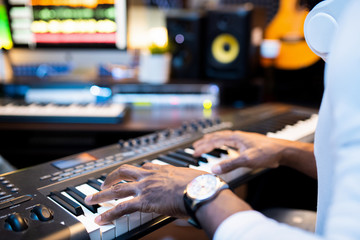 Hands of young African-american musician over keys of pianoboard working alone