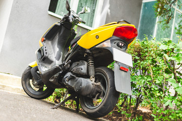 Eco Friendly yellow scooter parked on a sidewalk with copy space - Small and light mean of transportation in the town - Mobile and fast electric vehicle