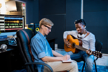 Two young multicultural men working over new song in sound recording studio