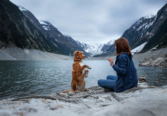 woman with a toller dog at the mountains lake. Traveling with a pet. Nova Scotia Duck Tolling Retriever