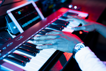 Hands of young contemporary musician over keys of pianoboard during making music