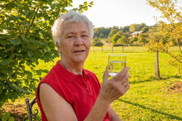 Senior citizen enjoys drinking a glass of water in the garden