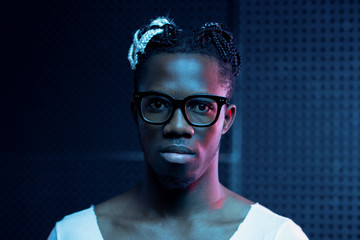 Young serious African man in eyeglasses and white t-shirt looking at you