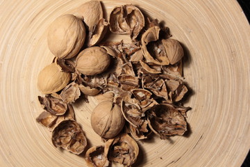 Crushed and whole walnuts in wooden plate