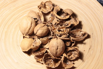Fototapeta na wymiar Crushed and whole walnuts in wooden plate
