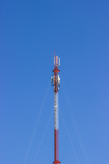 Red and white Telecommunication tower in a day of clear blue sky.