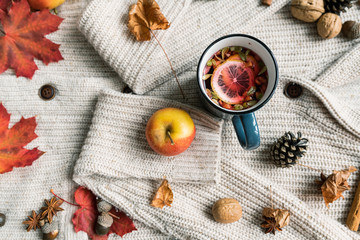 Ripe apple, mug of hot herbal tea with lemon, dry leaves, cone, nuts and spice