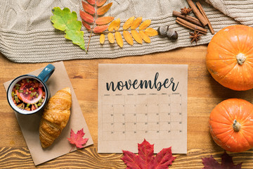 November calendar with hot drink and croissant, ripe pumpkins, leaves and spices
