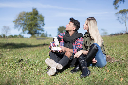 Couple sitting in the sun flying a drone