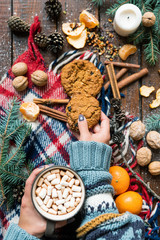 Young female hand taking cookie while having hot coffee with marshmallows