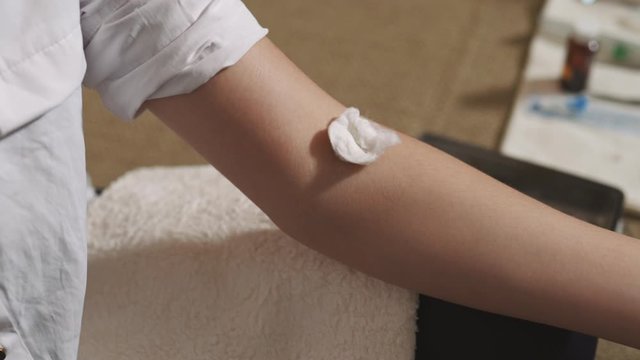 Sick caughing woman getting syringe drug injection by an experienced ambulance doctor - Needle close up and covering area with a sponge