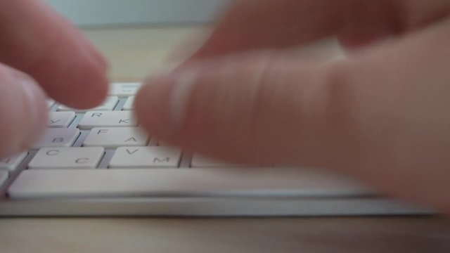 A man types on a white keyboard with the Cyrillic alphabet.