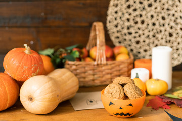 Group of ripe pumpkins, orange halloween plastic bowl with cookies