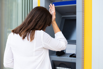 Stressed Woman Looking At Her Bank Account Balance At ATM