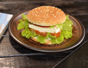Favorite food. On the table is a plate with a fresh, delicious burger.