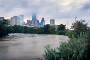 Spilled river and water flowing with great speed against the background of the city. Effects Tropical Storm Imelda. Houston, Texas, US