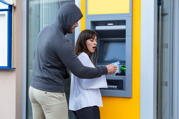 Thief Stealing Card From Woman Standing Near The Cash Machine