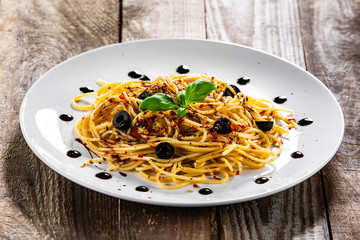 Pasta with black olives and chilli on wooden table