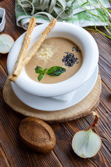 Mushroom soup with pasta with champignons and herbs on a brown wooden background