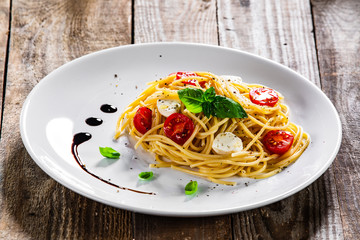 Pasta with cherry tomatoes and mozzarella cheese on wooden table