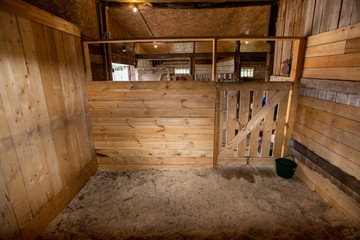 One of empty barns for racehorse surrounded by wooden walls and door