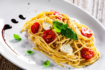 Pasta with cherry tomatoes and mozzarella cheese on wooden table