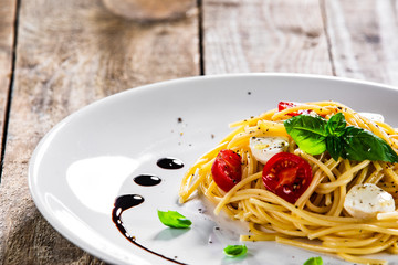 Pasta with cherry tomatoes and mozzarella cheese on wooden table