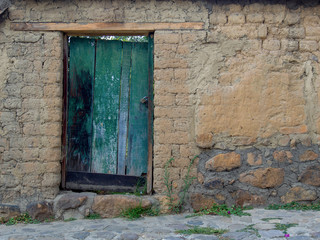 A very old green wooden door in ruins in a street at the colonial town of Villa de Leyva in the Andean mountains of central Colombia.