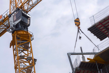 Tower mast crane. Hoisting block with hook on steel chain on the steel rope lift the huge steel beams. Loading\unloading of building materials on construction building site.
