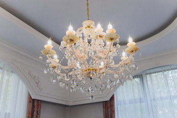 Close up on crystal of contemporary chandelier, is a branched ornamental light fixture designed to...