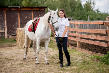 Young active woman chilling out with white purebred racehorse