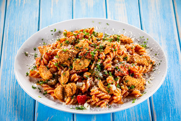 Pasta with tomato sauce and vegetables on wooden table