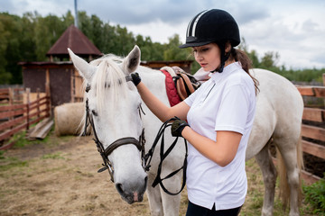 Active girl in equestrian helmet and her racehorse moving down field