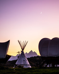 Teepees and covered wagons at sunset and moon set