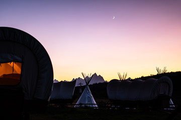 Fototapeta na wymiar Teepees and covered wagons at sunset and moon set