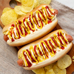 Delicious homemade colombian hot dogs with pineapple sauce, yellow mustard and mayo ketchup on a rustic wooden board, top view. Flat lay, from above, overhead. Closeup.