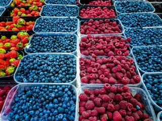 Various fresh berries Fruits in Plastic Trays on food market stall.