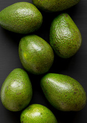 Whole avocados on a black surface, top view. Overhead, from above. Close-up.