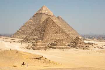 Fototapeta na wymiar Tourists on camels are seeing Giza pyramids