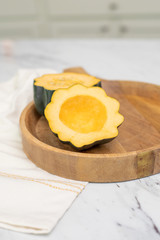 Acorn Squash Cut Open on Wooden Tray; One Half has Seeds Scooped Out