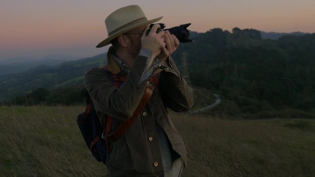 Man taking photos on hilltop at sunset