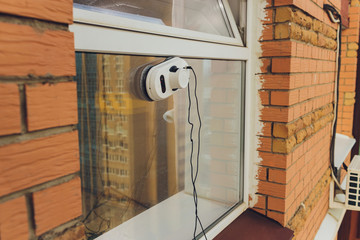 Vacuum cleaner robot cleaning window in high building outdoor.