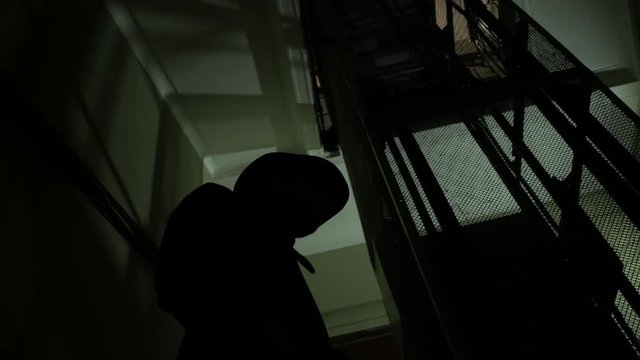 Silhouette of spy man with hat in the dark corridor 