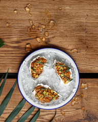 Salmon tartar on ice crumb on a plate on a wooden table. Original restaurant serving. Top view.
