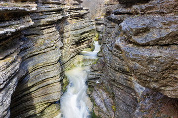 Beautiful narrow slot canyon and a mountain creek streaming through the eroded, textured rocks